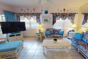 A living room with a television, two sofas, a coffee table, and a TV stand. - Family friendly seven mile beach condo.Cayman gem . (George Town)