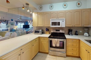 A kitchen with wooden cabinets, a microwave, a toaster, and a stove. - Family friendly seven mile beach condo.Cayman gem . (George Town)