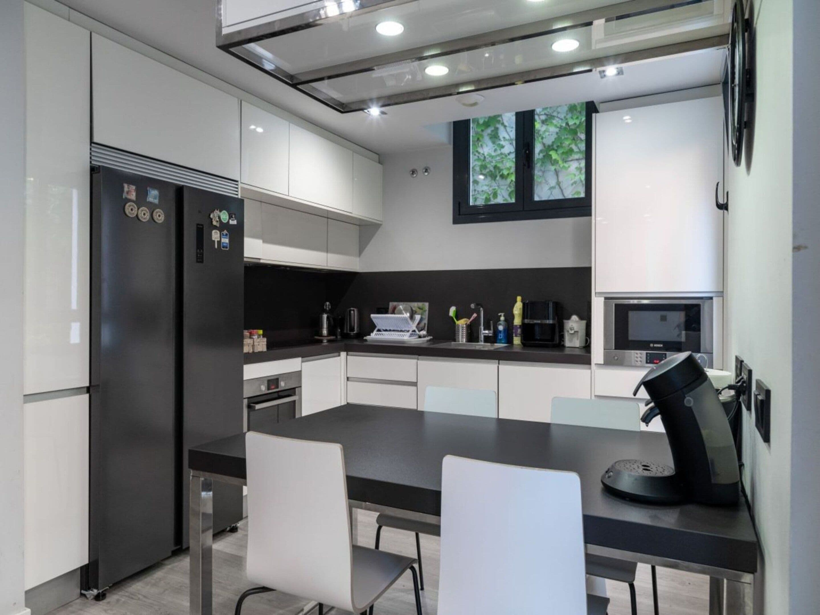 A modern kitchen with a refrigerator, microwave, and coffee machine.
