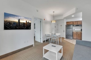 Un appartement moderne offrant une vue sur la ville, comprenant un coin repas, une kitchenette et un salon.