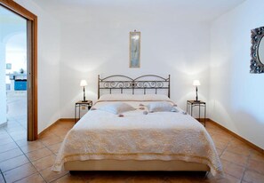 A bedroom with a bed, two bedside tables with lamps, a wall-mounted mirror, and a door leading to an outdoor area. - Casa Eritia (Positano)