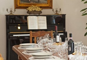 A dining table set for a meal with a piano and sheet music in the background. - Casa Eritia (Positano)