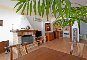 A spacious living area with a fireplace, television, and wooden furniture. - Casa Eritia (Positano)