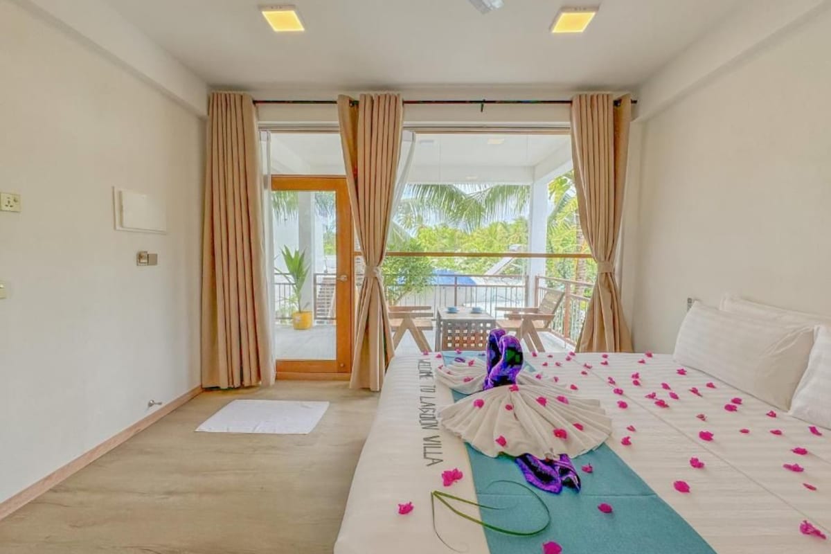 A hotel room with a bed, a balcony, and a view of the outdoors.