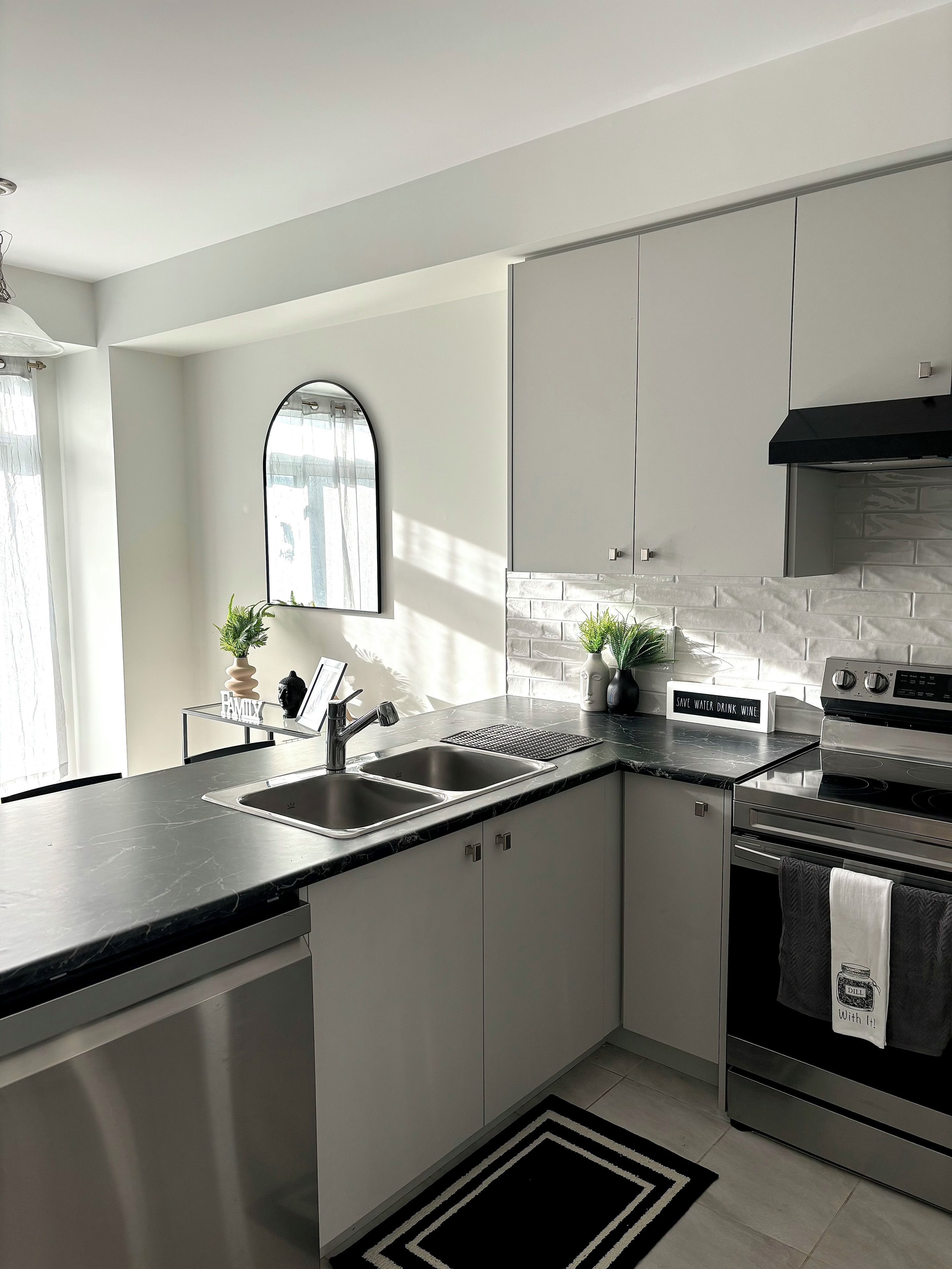 Eine moderne Küche mit schwarzem Arbeitsplatten, Edelstahlgeräten und einer Spritzschutzwand.