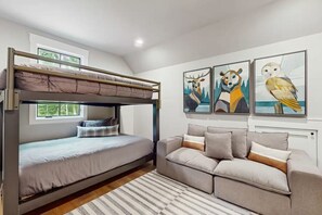 Una habitación con una cama individual, un sofá y tres cuadros enmarcados con motivos de animales en la pared.