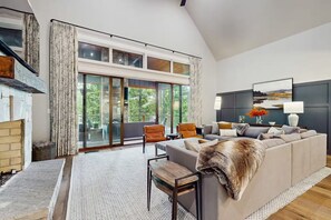 Un salon spacieux avec une cheminée, un grand canapé et une vue sur l’extérieur.
