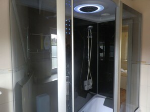 A modern bathroom with a glass-enclosed shower, a visible control panel, and a ceiling light fixture. - Holiday Home With 1 Bedroom (Wyk auf Foehr)