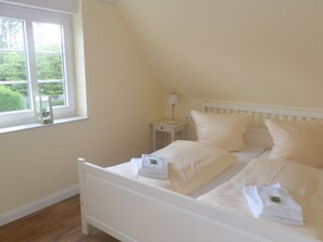A bedroom with a single bed, a bedside table with a lamp, and a window with a view of greenery. - Holiday Home With 1 Bedroom (Wyk auf Foehr)