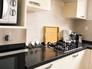 A modern kitchen with a gas stove, coffee maker, and wine glasses on the counter. - Luxurious Villa in Gammarth, Tunisia With Private Pool (La Marsa)
