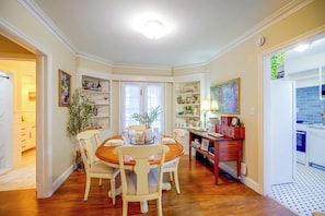 A dining area with a wooden table and chairs, surrounded by shelves with various items. - Shop, Dine, Walk Dtwn! Snowbird Stay in Vero Beach (Vero Beach)