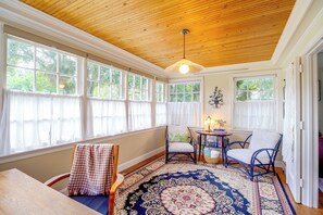 A sunlit room with a wooden ceiling, large windows, a patterned rug, and wicker furniture. - Shop, Dine, Walk Dtwn! Snowbird Stay in Vero Beach (Vero Beach)
