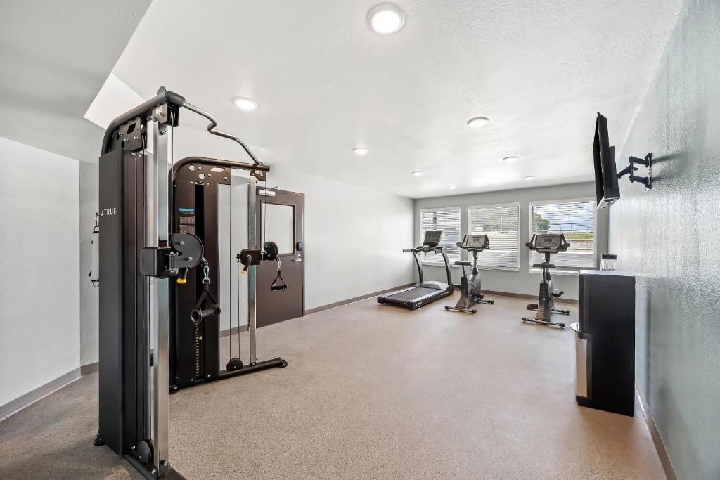 Een fitnessruimte met trainingsapparatuur, een loopband en een aan de muur bevestigde televisie.