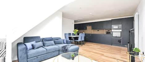 A modern living space with a sofa, coffee table, and dining area.