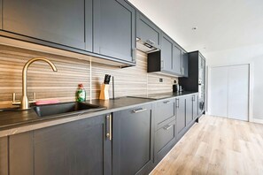 Eine moderne Küche mit dunklen Schränken, einer Edelstahl-Spüle und einer Holzrückwand.