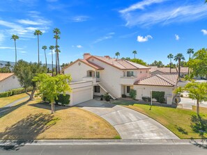 A residential area with houses featuring red-tiled roofs, a central driveway, and palm trees. - Desert Falls Escape Golf, Pools & Mountain Views (Palm Desert)