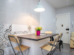 A modern kitchen with a central island, two chairs, a hanging light fixture, and patterned backsplash tiles. - Lush Home in Retiro, Madrid (Madrid)