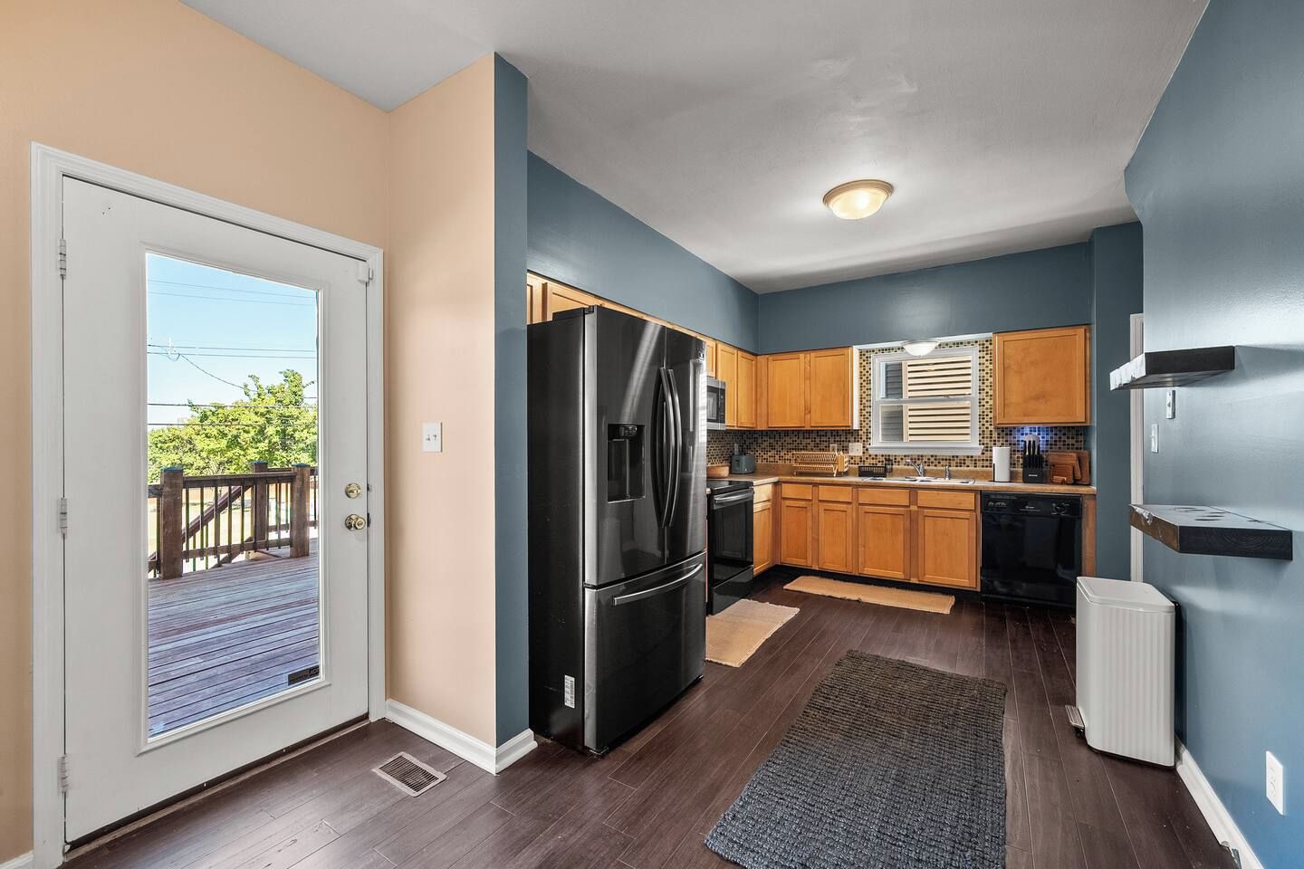 A modern kitchen with wooden cabinets, a black refrigerator, and a built-in oven.