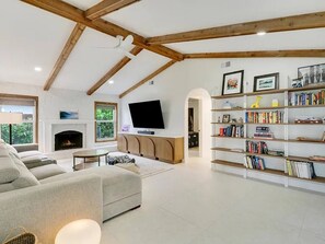 Amplia sala de estar con chimenea, televisor de pantalla plana, estantería y un ventanal grande.