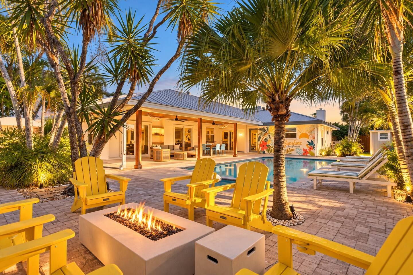 A poolside area with yellow Adirondack chairs, a fire pit, and a pool.