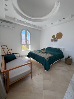 A bedroom with a bed, a chair, a window, and a ceiling with a circular design. - Dar Lisa - Charming, Authentic Seaside Villa (Djerba Midun)