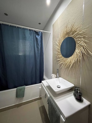 Un baño moderno con bañera, lavamanos y espejo con diseño de sol.
