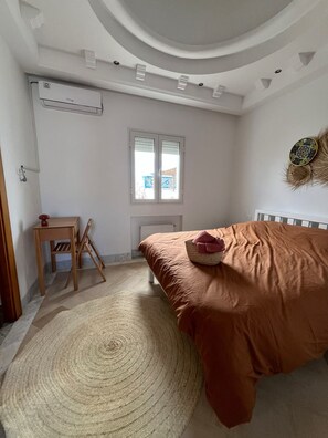 Un dormitorio con cama, una silla de madera, una ventana y un radiador.