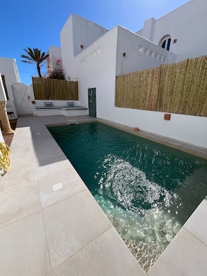 A swimming pool with a clear blue water surface, surrounded by white walls and a tiled deck. - Dar Lisa - Charming, Authentic Seaside Villa (Djerba Midun)