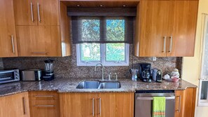 Ett kök med träskåp, en bänkskiva i granit, ett handfat, en brödrost, en mixer, en kaffebryggare och en diskmaskin.