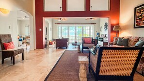 A spacious living room with a high ceiling, a large window, and a view of the outdoors. - ccLarge Luxurt\  Home for Groups & Families, Direct on Beach w.Golf Cart (Dorado)