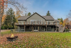 A two-story house with a balcony, a fire pit, and a staircase leading to the upper level. - The Lobster Cottage - Acadia National Park Retreat (Lamoine)