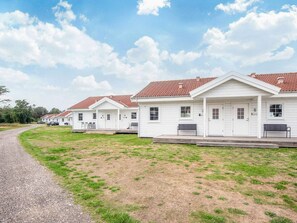 A row of white buildings with red-tiled roofs, a gravel path, and a grassy area. - 4 Person Holiday Home in Laeso (Læsø)