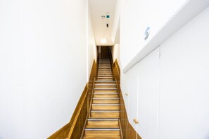 A narrow stairway with wooden steps and a white wall on one side. - West Kensington 2BR | 1-Min Tube | Heathrow Direct (Greater London)