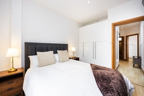 A hotel room with a bed, bedside tables, a wardrobe, and a mirror. - West Kensington 2BR | 1-Min Tube | Heathrow Direct (Greater London)