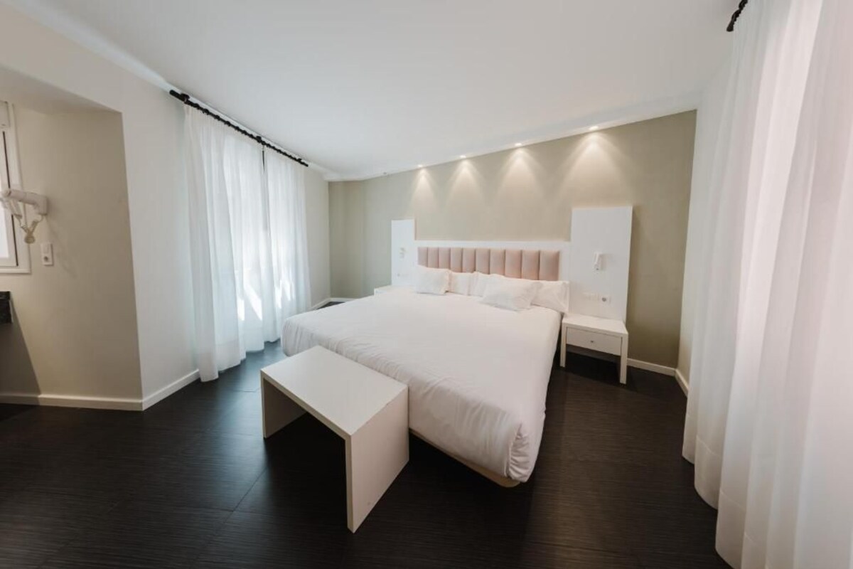 Una camera da letto moderna con un letto grande, comodini, una panca e una testiera.