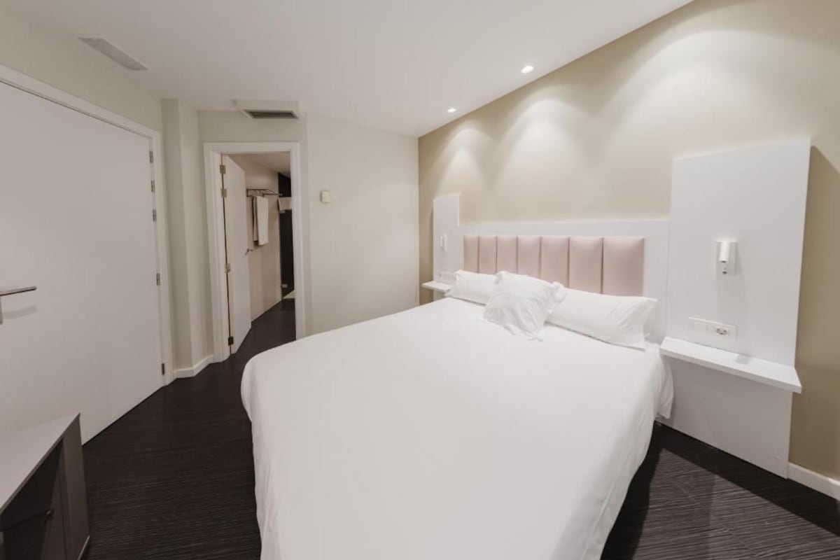 Una camera d'albergo con un letto, un armadio, una scrivania e una cabina armadio.