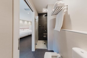 Un bagno moderno con doccia, servizi igienici e una piccola zona relax con una panca.