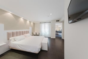 Una camera d'albergo moderna con un letto grande, comodini, una TV a schermo piatto e vista sul bagno.
