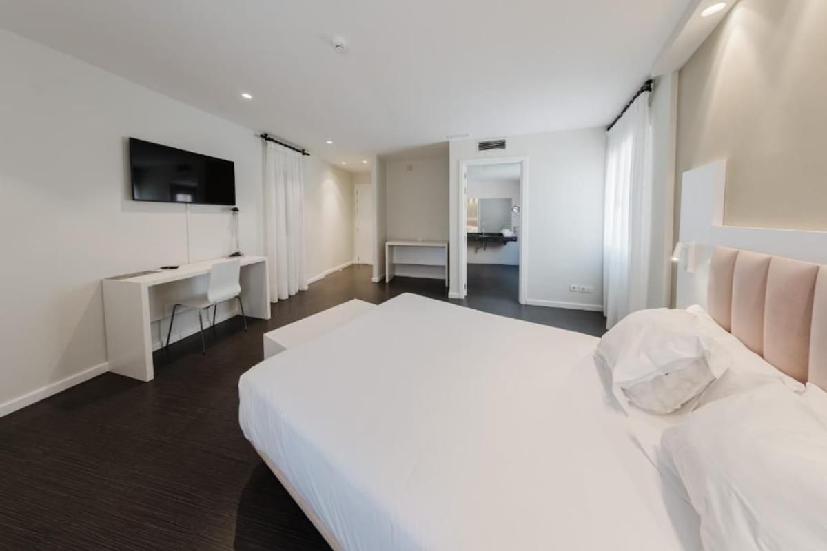 Una camera d'albergo moderna con un letto grande, una scrivania e una televisione.