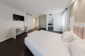 Una camera d'albergo moderna con un letto grande, una scrivania e una televisione.