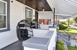 A covered porch with two black wicker swing chairs and a grey bench. - Cincy 5BR Escape Zoo Xavier Sleeps 7 (Cincinnati)