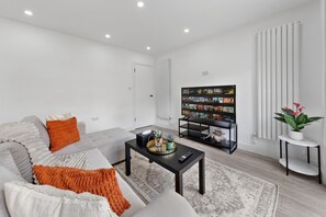 A modern living room with a sofa, coffee table, and a flat-screen TV. - Luxury Suite with Private Balcony - Edgware Rd (London)