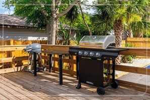 An outdoor grill setup on a wooden deck with a wooden fence in the background. - 3-BR Beach House in enchanting St. Petersburg Pool, Grill & More (St. Petersburg)