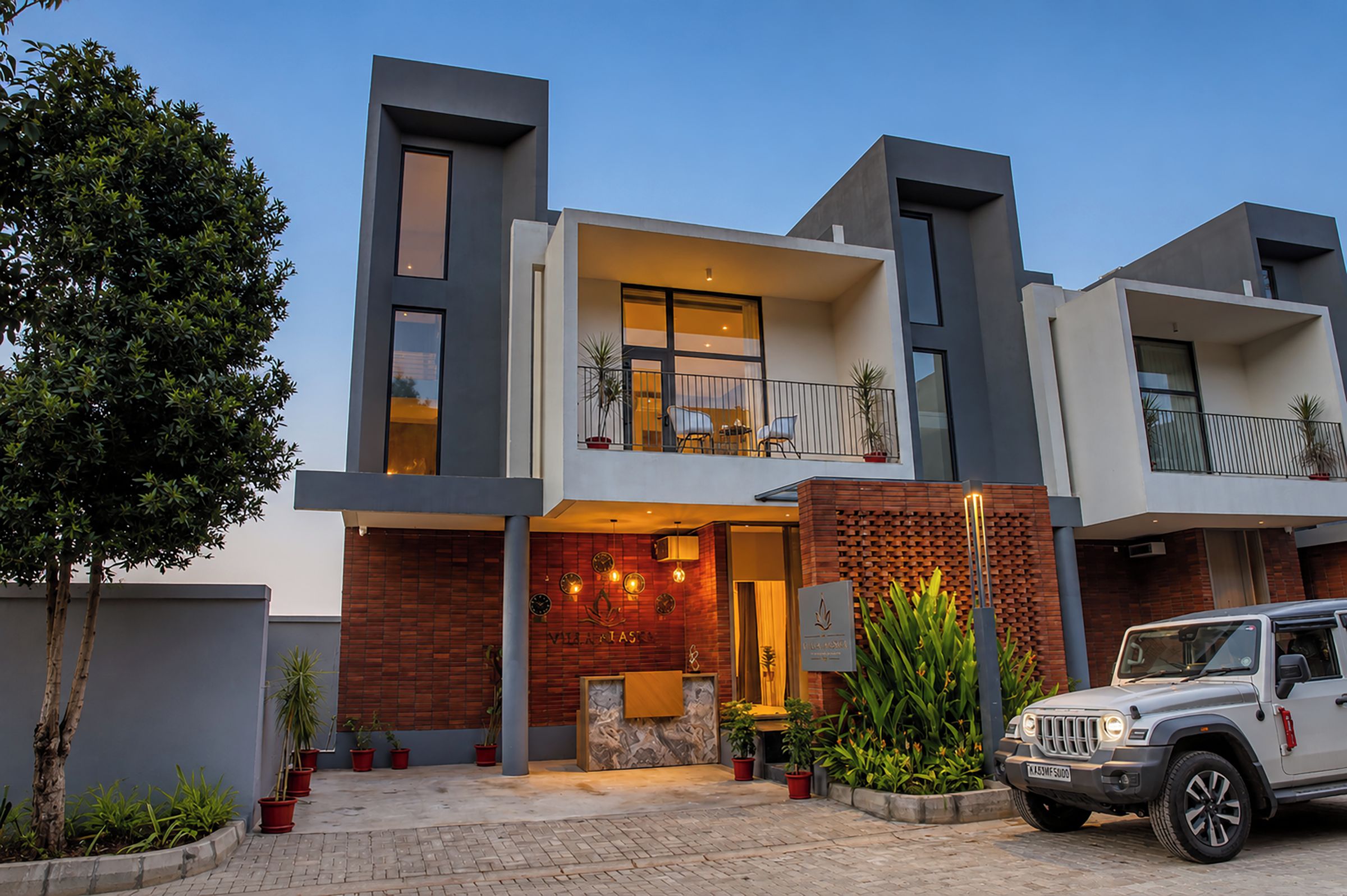 A modern two-story building with a balcony, a brick facade, and a parked vehicle.