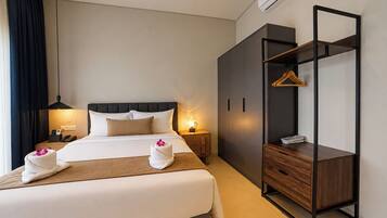 Una habitación de hotel con una cama, mesitas de noche, un armario y un ropero.