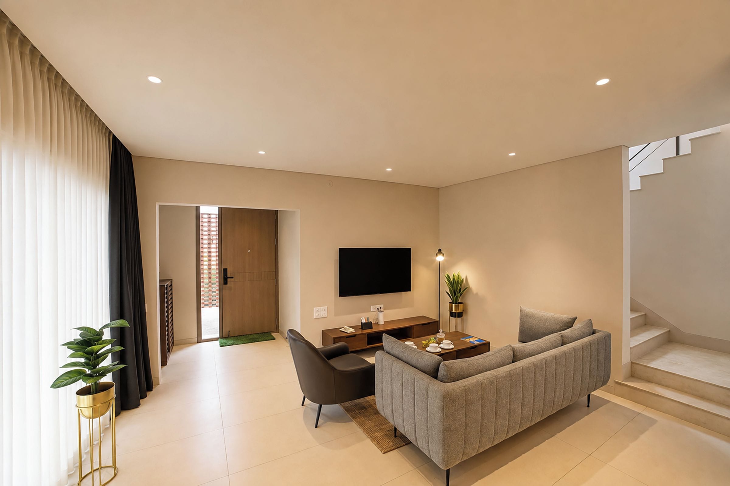 Un salon moderne avec un canapé, une table basse, un téléviseur et un escalier.