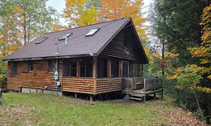 A log cabin with a porch and a small deck, surrounded by trees with autumn foliage. - Secluded 2BR Log Cabin On 52 Wooded Acres (Norway)
