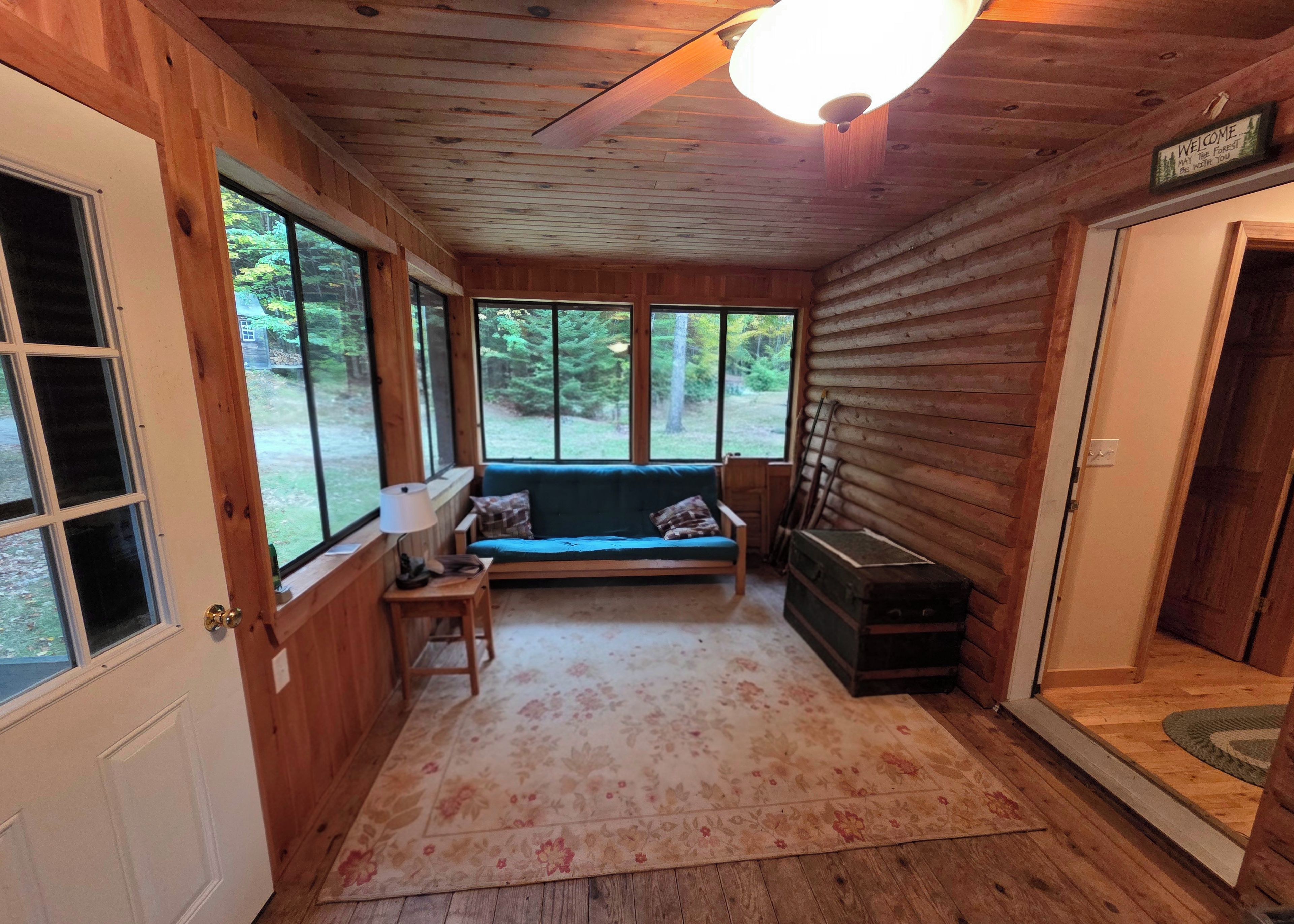 A log cabin interior with a bench, a lamp, and a suitcase.