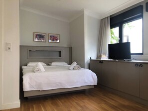A hotel room with a bed, a television, a desk, and two framed pictures on the wall. - Rich Area In Istanbul Suite 4 (Istanbul)