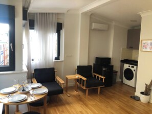 A compact living space with a dining area, two sofas, a small table, and a kitchen area with a washing machine. - Rich Area In Istanbul Suite 4 (Istanbul)